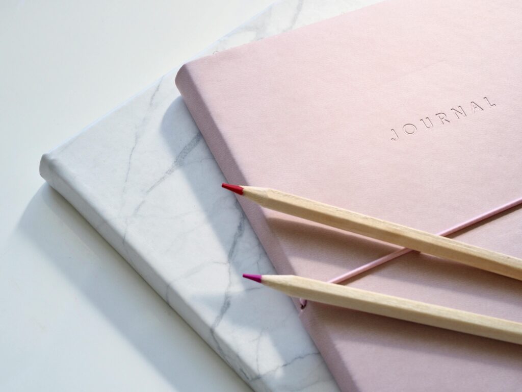 pexels photo 1018133 1018133 Close-up of a pink journal with pencils on a marble top. Perfect for note-taking or planning.