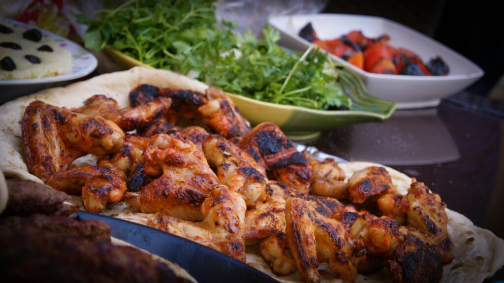 pexels photo 106343 106343 A close-up of grilled chicken wings served with fresh herbs and vegetables, perfect for culinary presentations.