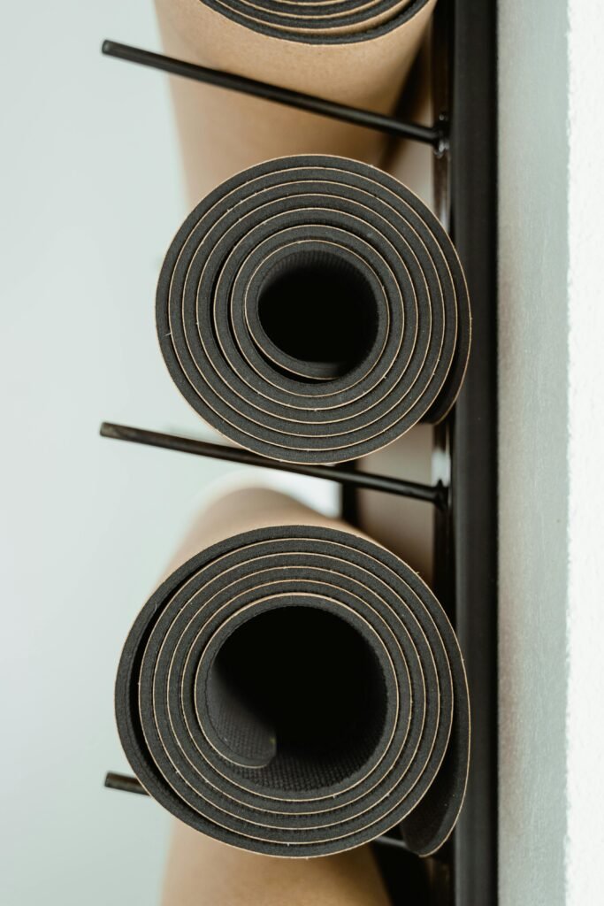 pexels photo 7319812 7319812 Rolled yoga mats neatly stacked on a rack indoors, ideal for fitness or wellness themes.
