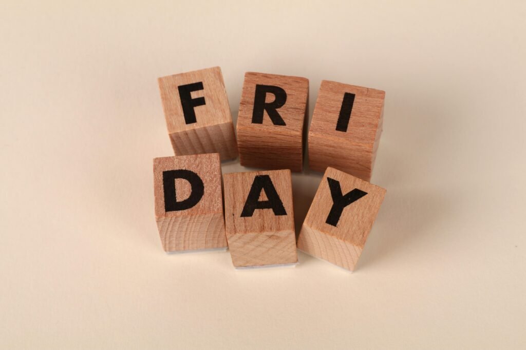 Wooden cubes spelling 'Friday' on a neutral surface with copy space.